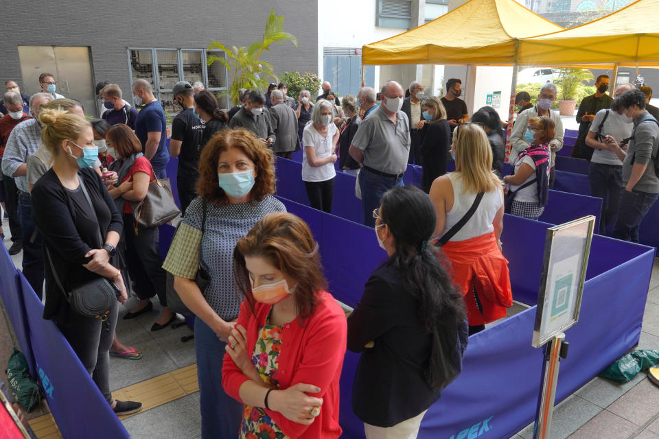 People queue up outside a vaccination center for BioNTech in Hong Kong Wednesday, March 24, 2021. Hong Kong suspended vaccinations using Pfizer shots - known as BioNTech shots in the city - on Wednesday after they were informed by its distributor Fosun that one batch had defective bottle lids. (AP Photo/Vincent Yu)