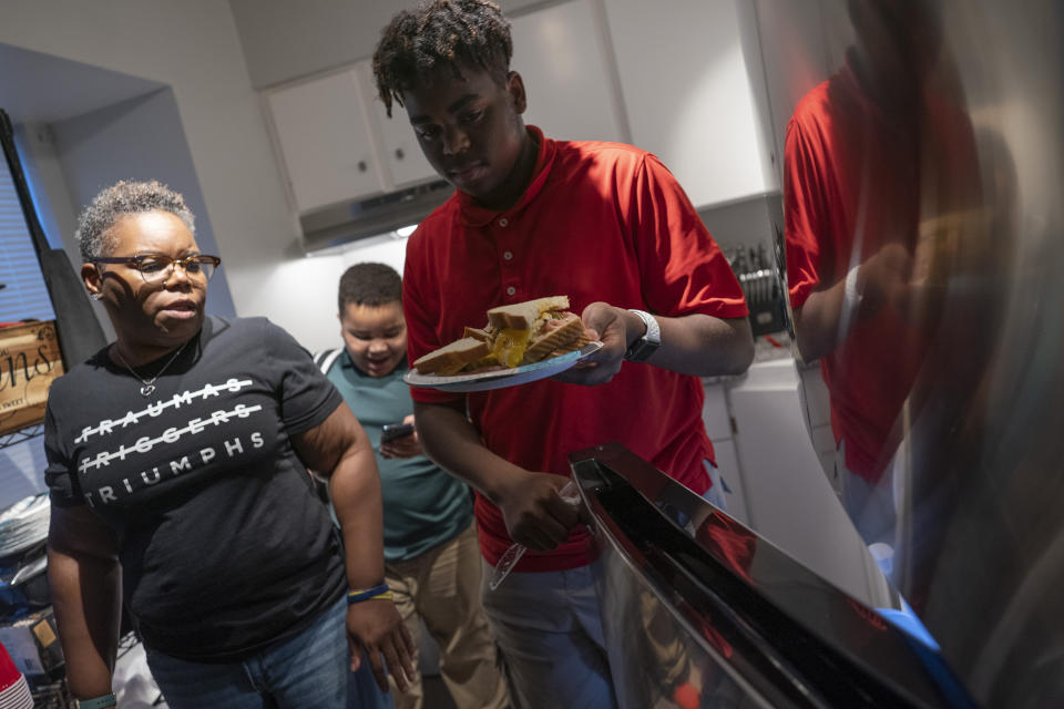 Melanese Marr-Thomas and her sons, Savion Thomas, center, and Zachary Marr, prepare dinner at home in District Heights, Md., on Wednesday, Sept. 21, 2022. (AP Photo/Wong Maye-E)