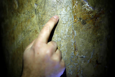 A researcher points at marks of crosses left by pilgrims on a pillar in the Cenacle, a hall revered by Christians as the site of Jesus' Last Supper, in Mount Zion near Jerusalem's Old City March 14, 2019. REUTERS/Amir Cohen