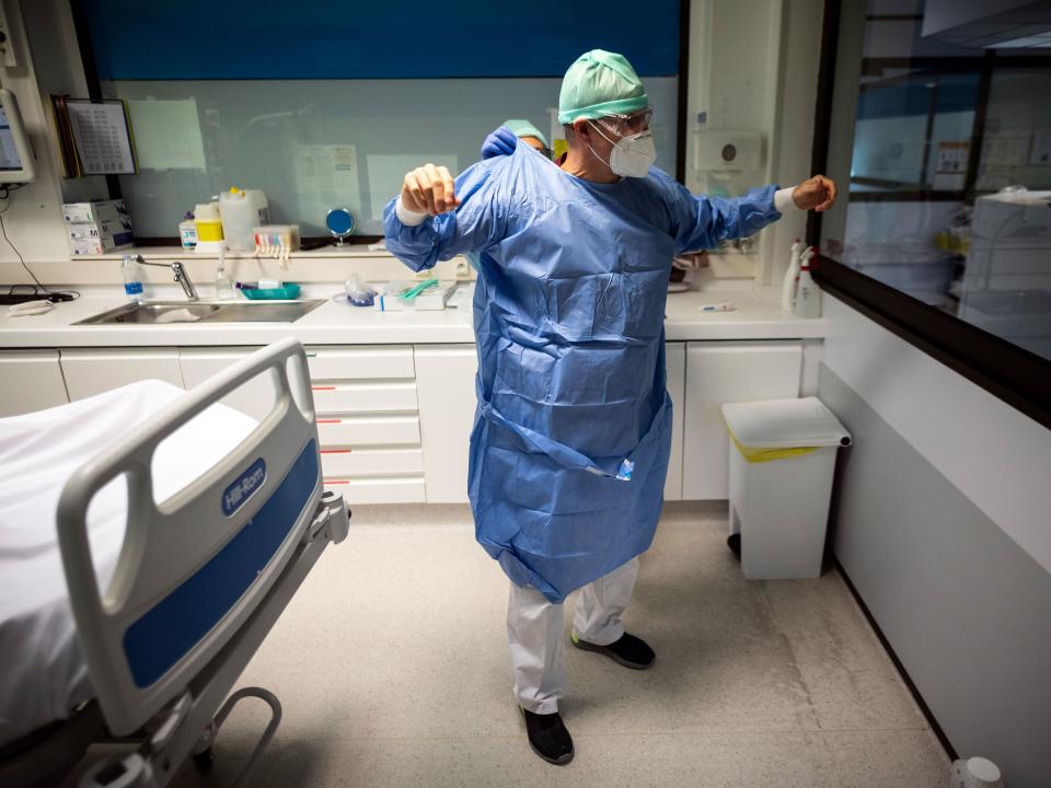 A nurse helps a doctor to put up his protective gear  (AFP via Getty Images)