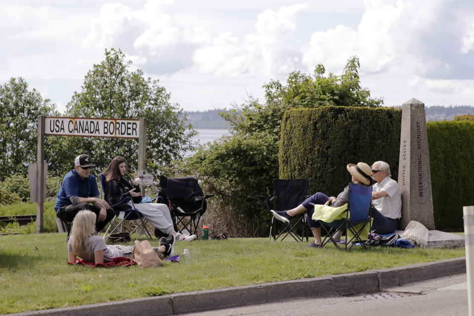 In this photo taken May 17, 2020, de Rham family members from the U.S. and Canada visit at the border between the countries in Peace Arch Park, in Blaine, Wash. With the border closed to nonessential travel amid the global pandemic, families and couples across the continent have found themselves cut off from loved ones on the other side. But the recent reopening of Peace Arch Park, which spans from Blaine into Surrey, British Columbia, at the far western end of the 3,987-mile contiguous border, has given at least a few separated parents, siblings, lovers and friends a rare chance for some better-than-Skype visits. (AP Photo/Elaine Thompson)