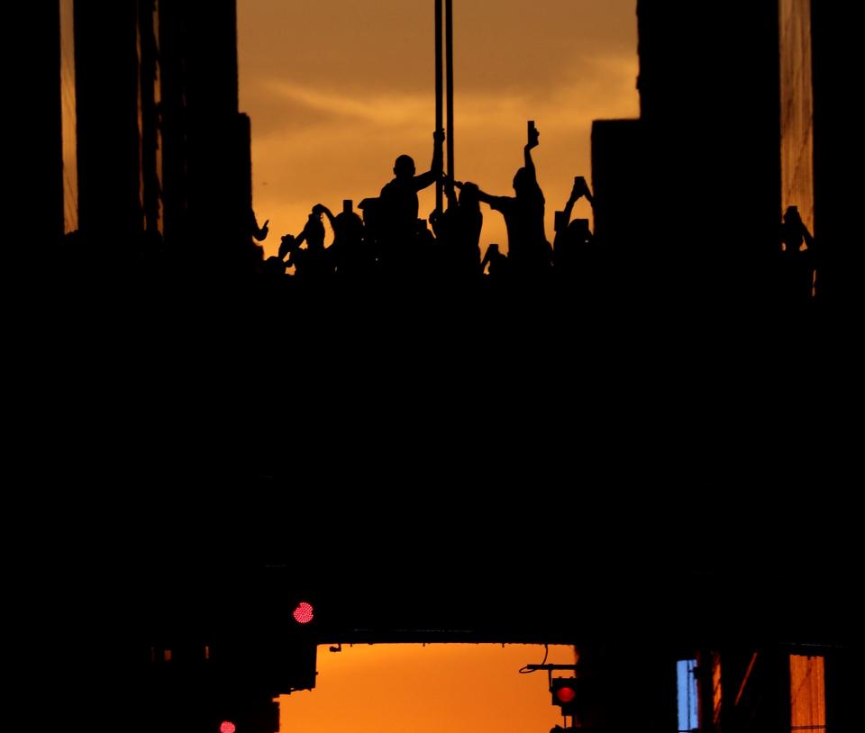 People stand on an overpass over 42nd St. in Manhattan July 11, 2022 to photograph the phenomenon known as Manhattanhenge.