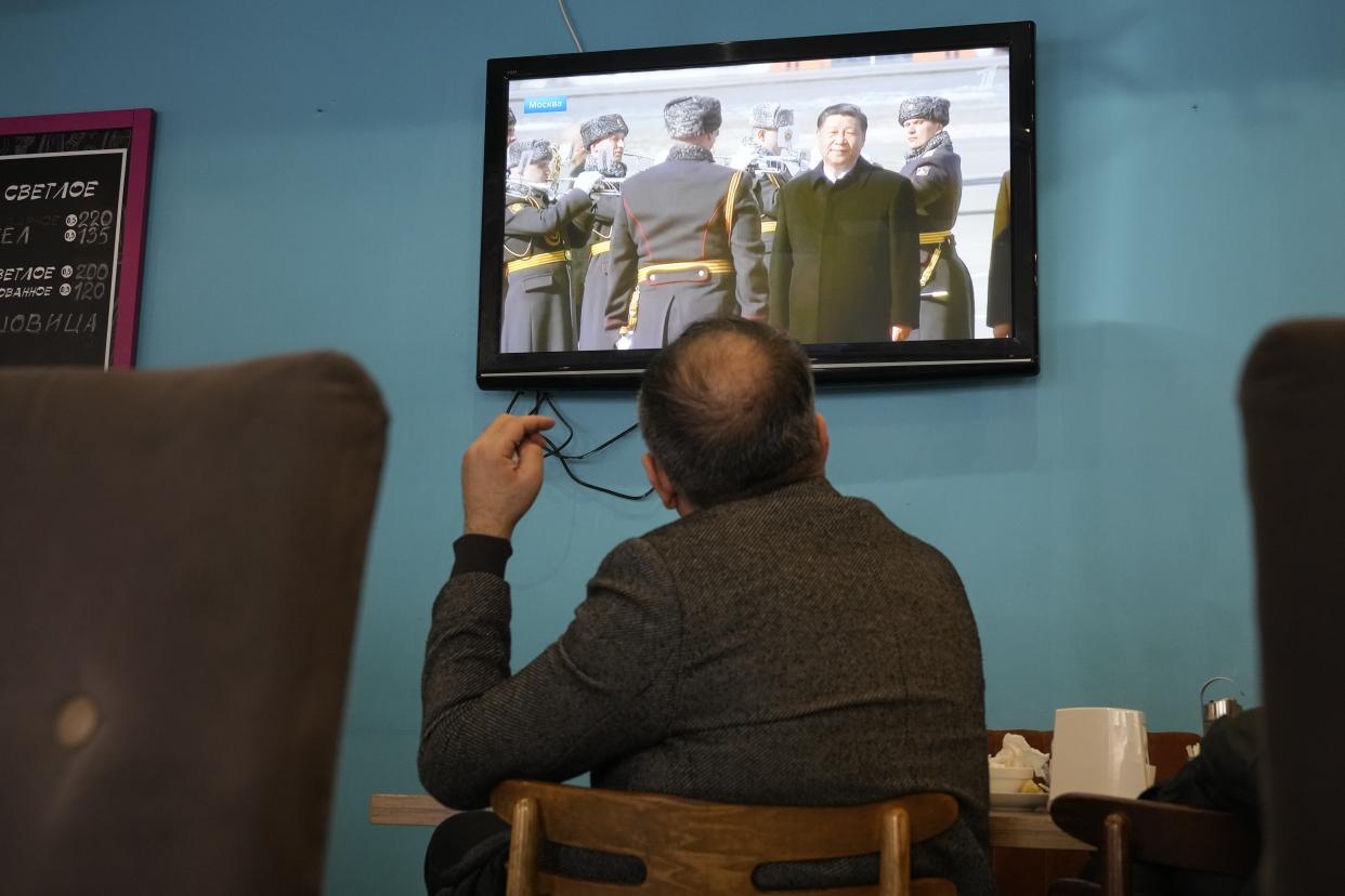 A TV screen displays Chinese President Xi Jinping attending an official welcome ceremony upon his arrival at the Vnukovo-2 government airport outside Moscow, in a cafe in St. Petersburg, Russia, Monday, March 20, 2023. (AP Photo)