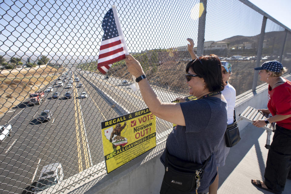 Volunteers wave flags and hold recall Gov. Gavin Newsom signs along the I-14 freeway at Golden Valley road in Santa Clarita, Calif., Monday, Sept. 13, 2021. Voting concludes Tuesday in California's recall election. (David Crane/The Orange County Register via AP)