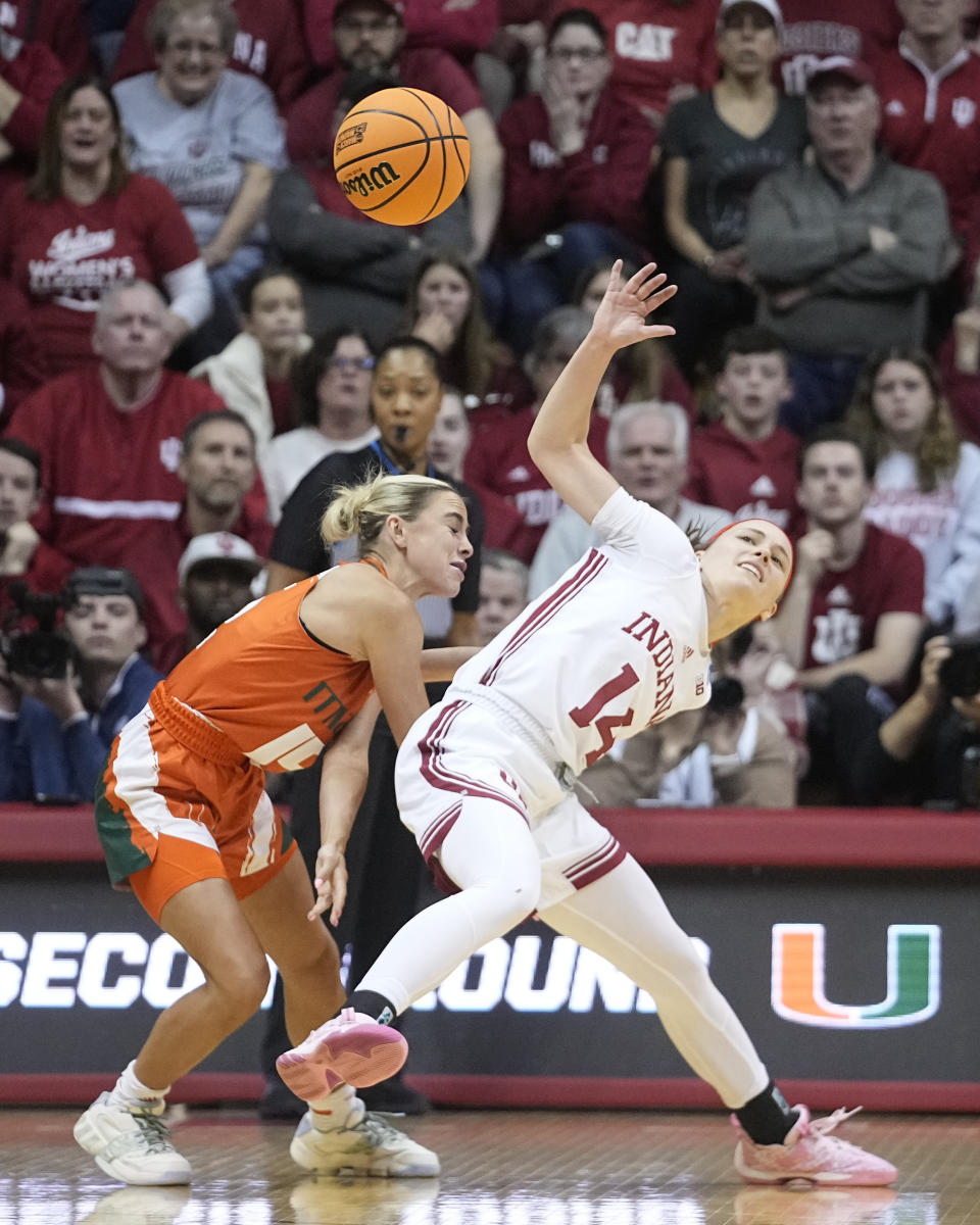 Miami's Haley Cavinder (14) and Indiana's Sara Scalia (14) go for a loose ball during the first half of a second-round college basketball game in the women's NCAA Tournament Monday, March 20, 2023, in Bloomington, Ind. (AP Photo/Darron Cummings)