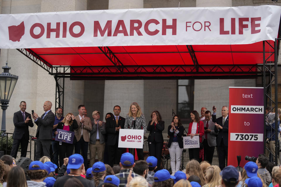 Ohio State Rep. Jennifer Gross, R-West Chester, holding a "Choose Life" sign, fourth from left, stands on stage as Ohio Sen. Kristina Roegner, R-Hudson, speaks during the Ohio March for Life rally at the Ohio State House in Columbus, Ohio, Friday, Oct. 6, 2023. The statewide battles over abortion rights that have erupted since the U.S. Supreme Court overturned a constitutional right to the procedure have exposed another fault line: commitment to democracy. (AP Photo/Carolyn Kaster)