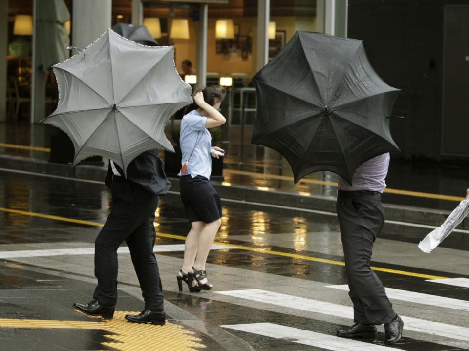People struggle to hold onto their umbrellas as Typhoon Bolaven brings heavy downpours and winds to South Korea, at Gimpo Airport in Seoul, South Korea, Tuesday, Aug. 28, 2012. (AP Photo/Ahn Young-joon)