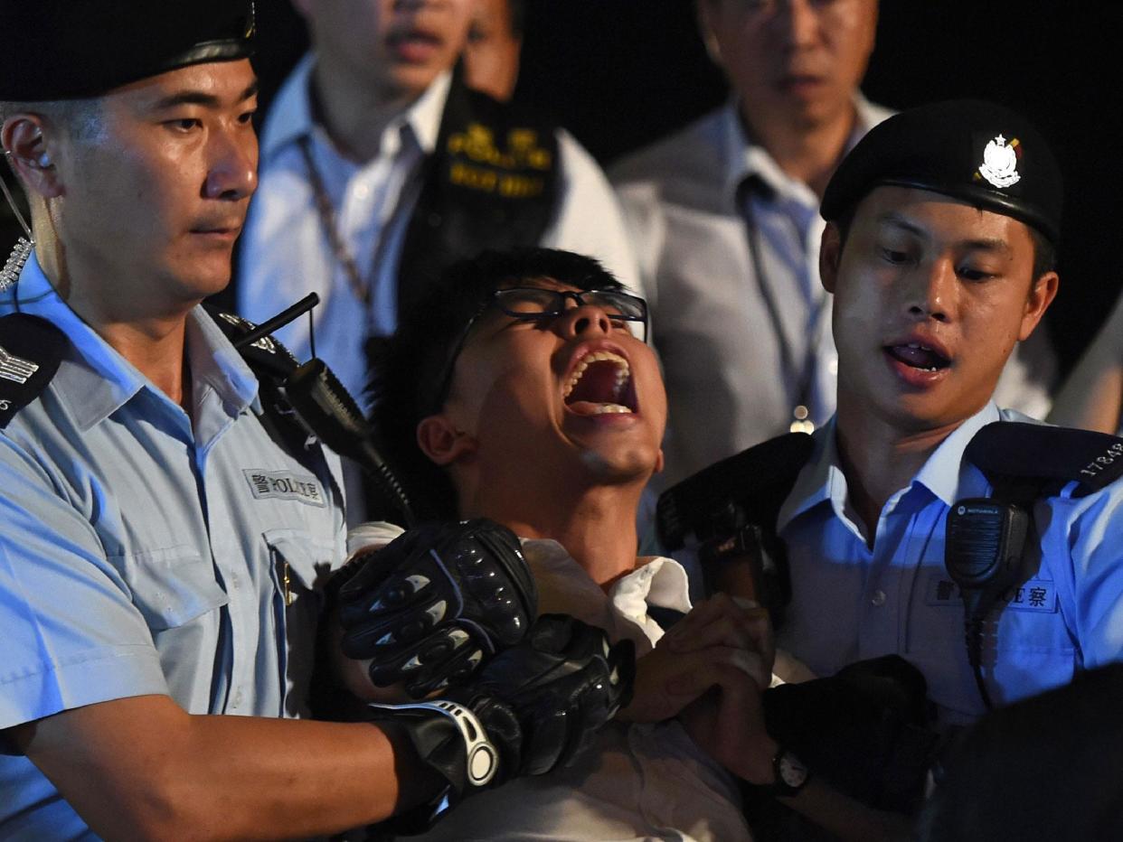 Pro-democracy campaigner Joshua Wong yells as he is taken away by police after he and other demonstrators staged a sit-in protest at the Golden Bauhinia statue, in front of the Convention and Exhibition Centre in Hong Kong: ANTHONY WALLACE/AFP/Getty Images