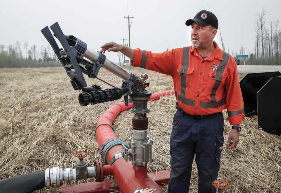 Derek Somerville, wildfire specialist with Fire & Flood Emergency Service Ltd., checks a wildfire suppression water cannon along highway 881 near Fort McMurray, Wednesday, May 15, 2024. (Jeff McIntosh/The Canadian Press via AP)