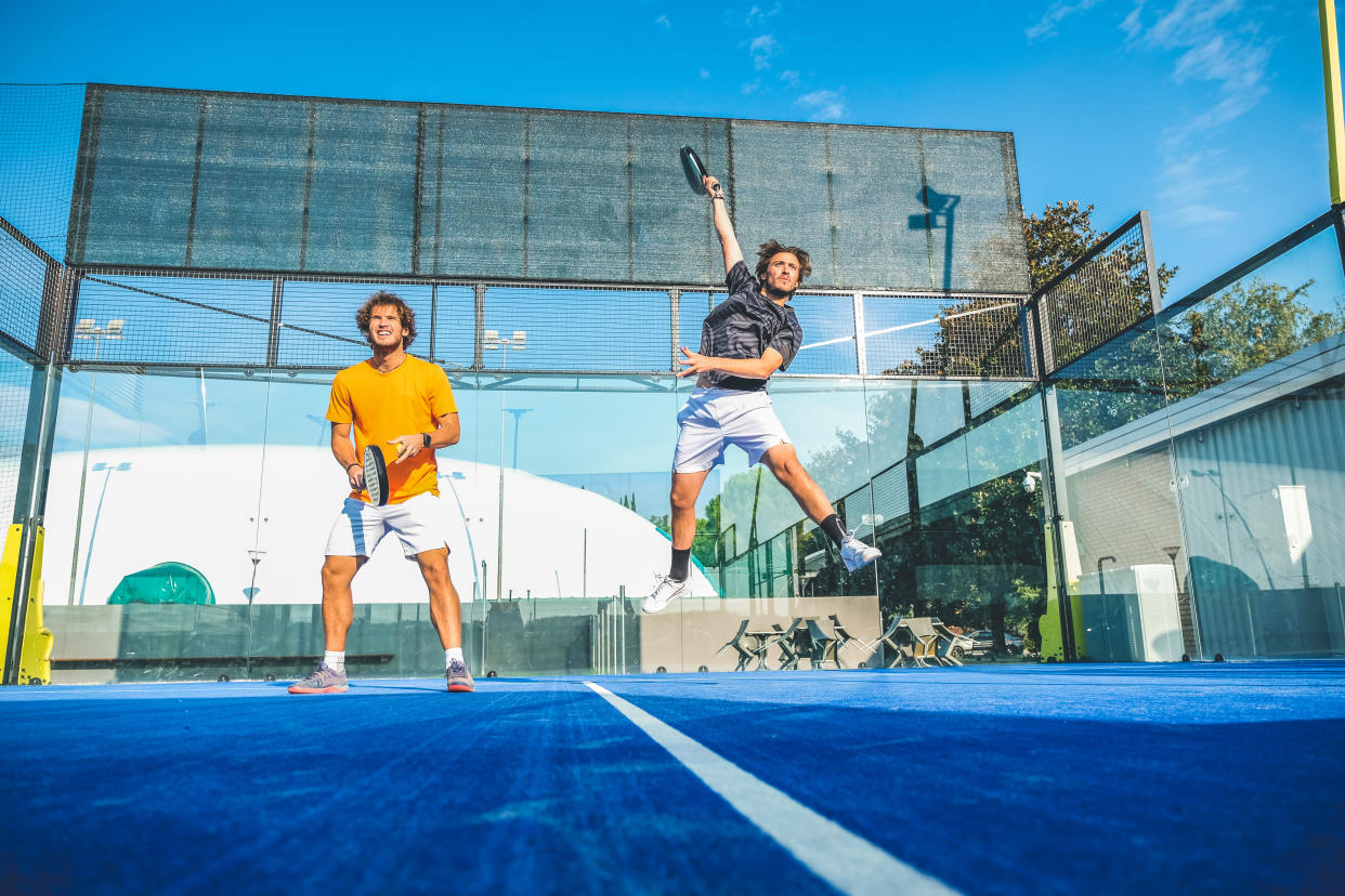 property Mixed padel match in a blue grass padel court - Beautiful girl and handsome man playing padel outdoor