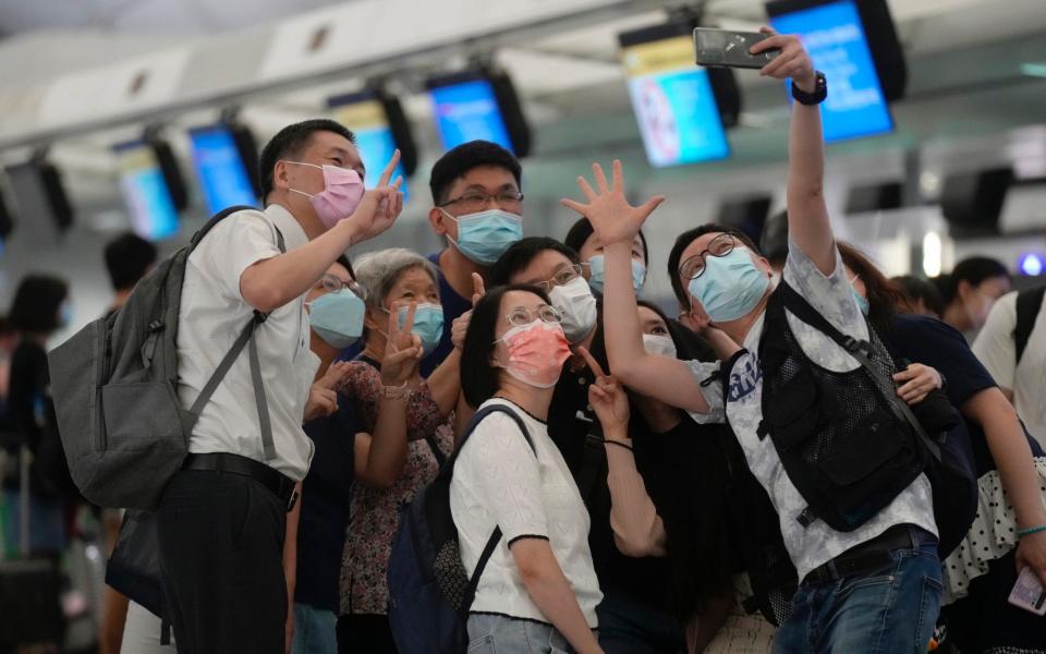 A group of people take a selfie at Hong Kong airport before their friend moves to the UK - Vincent Yu /AP