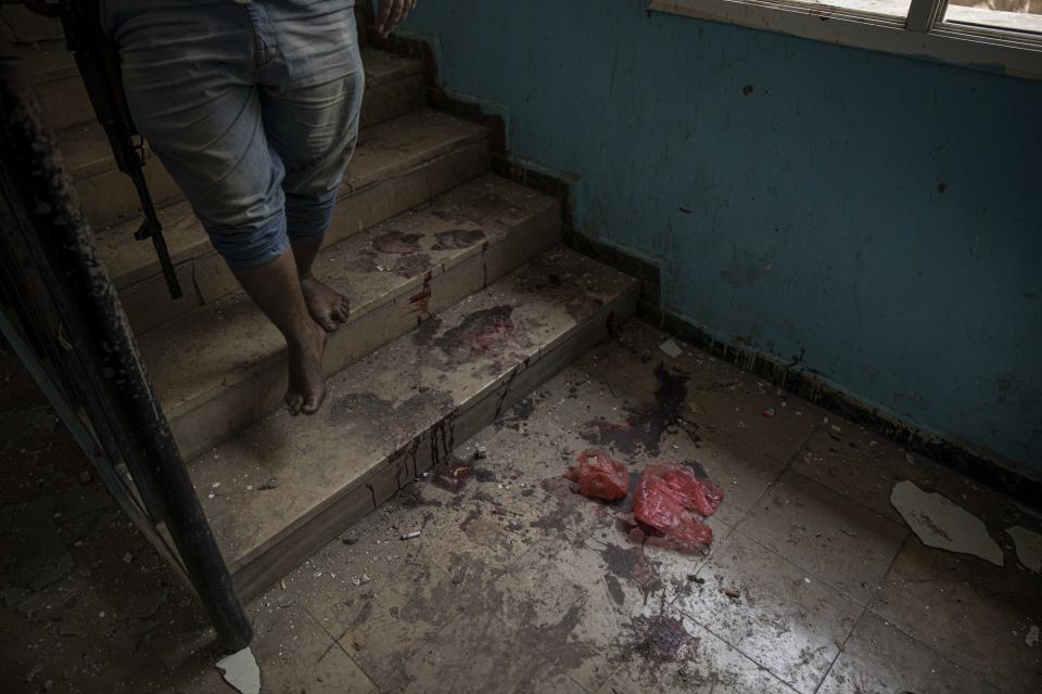 A solider walks past blood at the site of a deadly attack inside the Sheikh Othman police station in Aden, Yemen, Thursday, Aug. 1, 2019. Yemen's rebels have fired a ballistic missile at a military parade in the southern port city of Aden as coordinated suicide bombings targeted the police station in another part of the city. The attacks killed over 50 people and wounded dozens. (AP Photo/Nariman El-Mofty)