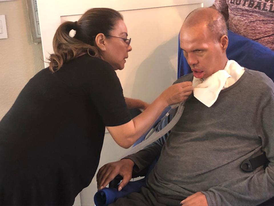 Chie Smith adjusts husband Steve's tracheostomy tube recently in their home in the suburbs of Dallas, Texas. Steve Smith has battled ALS for more than 15 years and cannot breath on his own. He was a star fullback on Penn State's last national championship team.