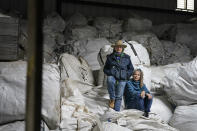 Gail Hepworth, right, and Amy Hepworth, sisters and co-owners of Hepworth Farms, pose for a picture on bags full of hemp plants at Hepworth Farms in Milton, N.Y., Monday, April 12, 2021. Farmers dealing with depressed prices for plants that produce CBD extract are eager to take part in a statewide marijuana market expected to generate billions of dollars a year once retail sales start. They already know how to grow and process cannabis plants, since hemp is essentially the same plant with lower levels of THC, marijuana's active ingredient. Now they're waiting on rules that will allow them to switch seeds. (AP Photo/Seth Wenig)