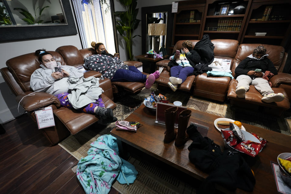 Una familia descansa y se protege del frío en los sillones de la mueblería Gallery Furniture, en Houston, que fue abierta por su dueño para albergar a personas afectadas por la tormenta invernal y los apagones. (AP Photo/David J. Phillip)