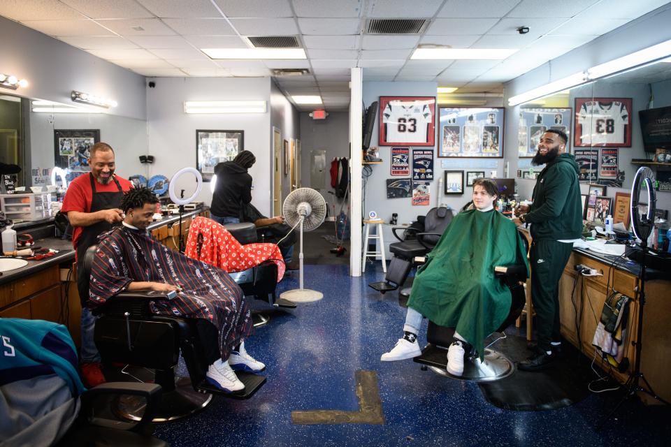 Barber Bobby Smith, left, gives a trim to his son, Storm Smith, while Jonathan McPherson Jr. cuts Nathan Rein’s hair at Platform Dzynz Barber Studio at 6257 Raeford Road.