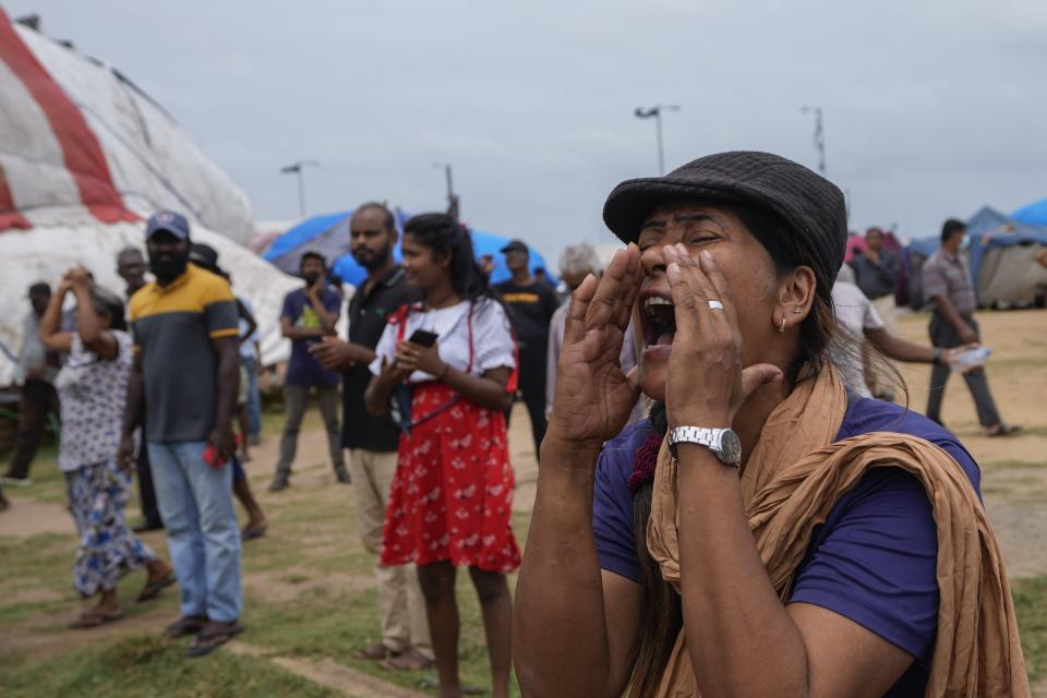 A woman reacts to a police announcement aired using loudspeakers ordering protesters to vacate the site of months long anti government protests outside the president's office in Colombo, Sri Lanka, Thursday, Aug. 4, 2022. Sri Lanka's Parliament approved a state of emergency July 27. The decree gives the president the power to make regulations in the interest of public security and order. (AP Photo/Eranga Jayawardena)