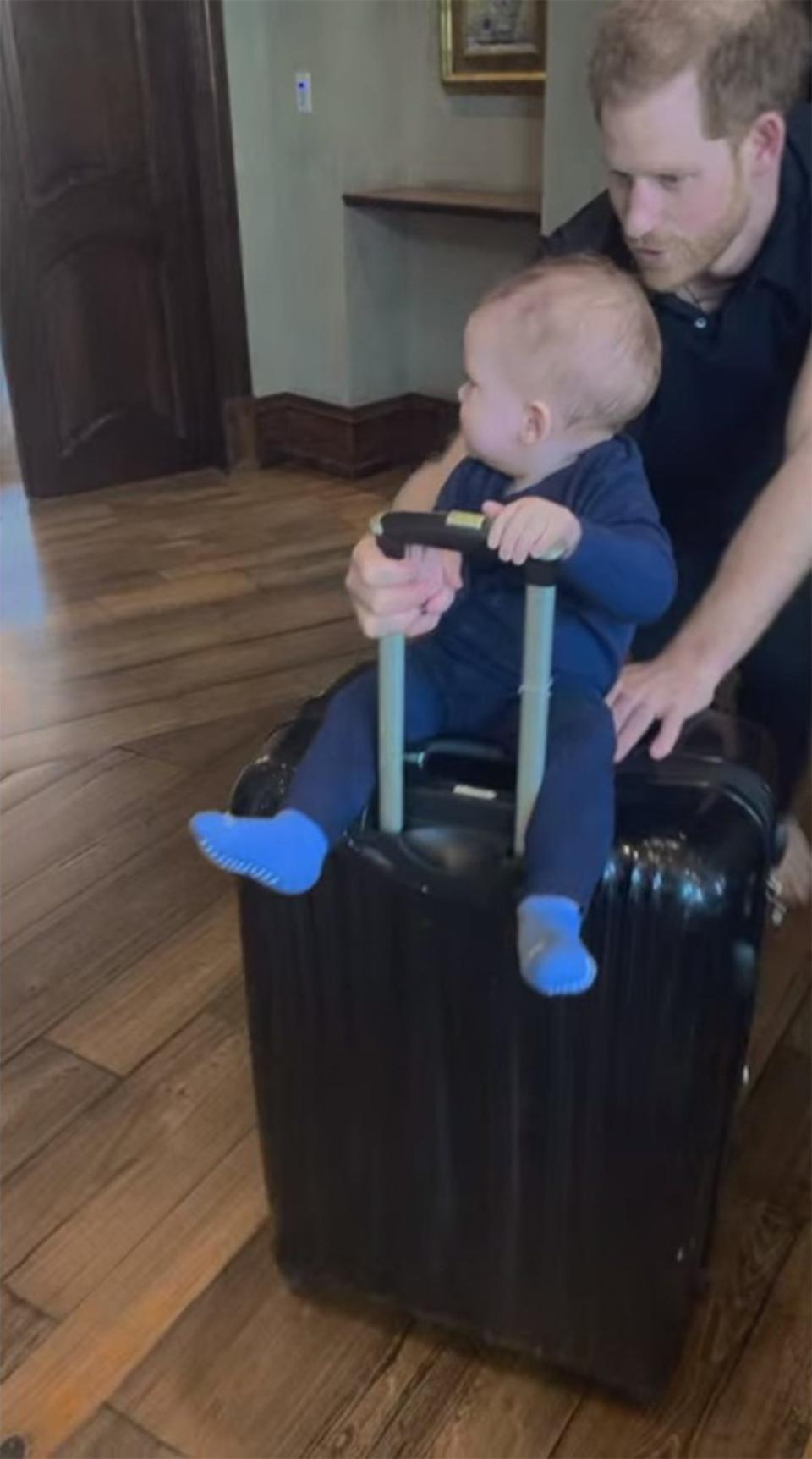 <p>Prince Harry gets his little guy ready for an adventure with a rolling suitcase ride.</p>