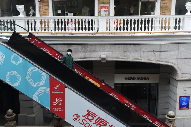 Man wearing a face mask rides on an escalator at a shopping complex in Wuhan