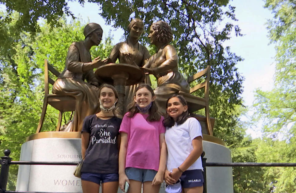 Jaya Shri, 13, , right stands with friends at the unveiling of a new statue honoring suffragettes in Central Park on Wednesday, Aug. 26, 2020. bronze statue depicting women’s rights pioneers Sojourner Truth, Elizabeth Cady Stanton and Susan B. Anthony was unveiled in Central Park on Wednesday. It's the 167-year-old park’s first monument honoring real historical women — as opposed to fictional heroines like Alice in Wonderland and Shakespeare’s Juliet. (AP Photo/Ted Shaffrey)