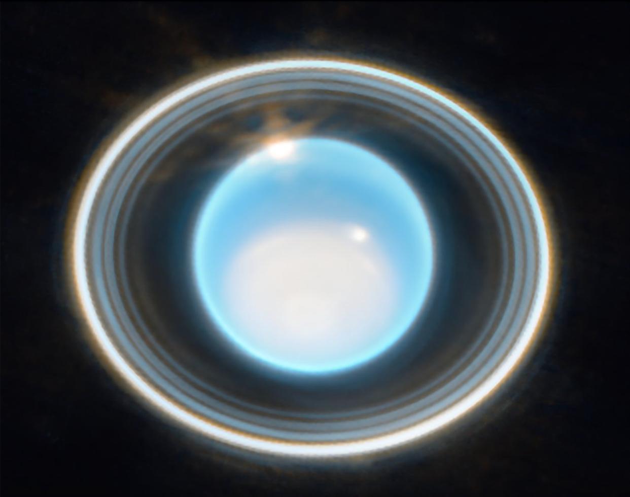  Closeup photo of five distinct rings around the blue planet uranus. 