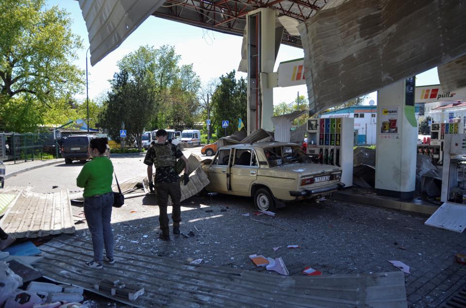 People are seen at a gas station damaged by a Russian military strike (REUTERS)
