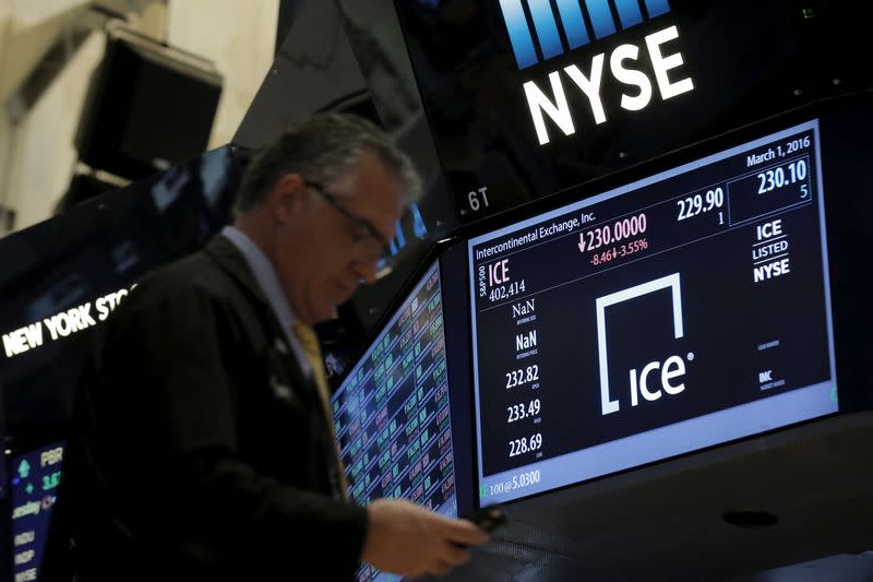 FILE PHOTO: A trader passes by a screen that displays the trading info for Intercontinental Exchange Inc. (ICE) on the floor of the NYSE