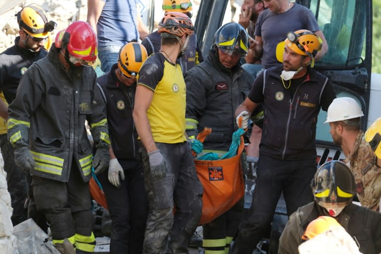 Rescuers carry the body of a victim in the Italian central village of Illica, near Accumoli, on August 24, 2016