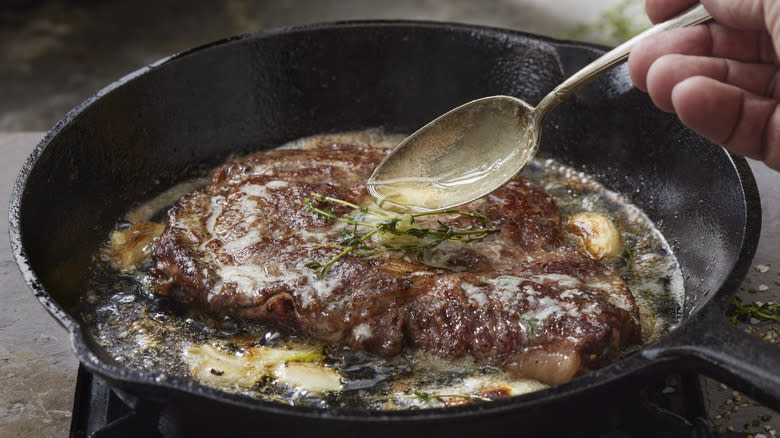 Ribeye steak cooking in butter in pan