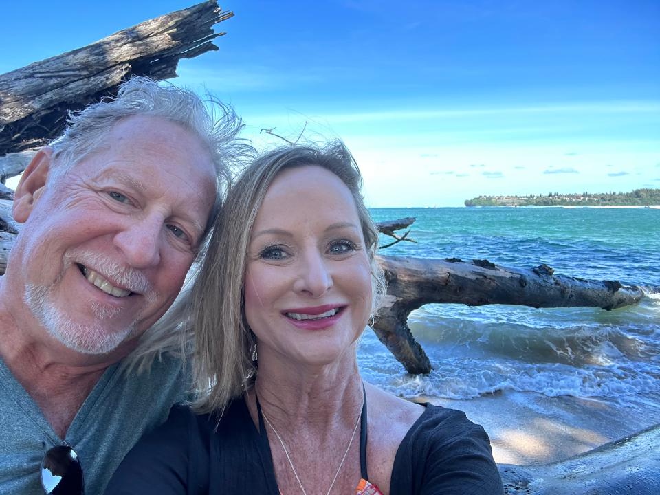 The author and her fiancé, Bobby, smiling and sitting on the beach in front of the ocean.