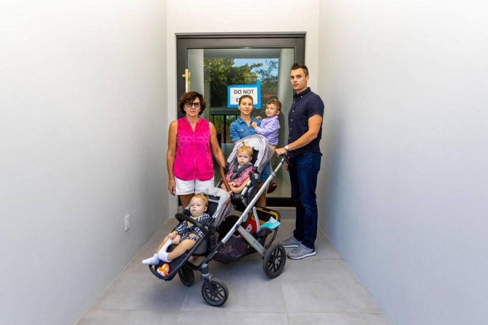 Michael Coyne y su familia junto a la puerta de su casa adosada en Coconut Avenue, construida por Doug Cox. Coyne pagó un depósito de $487,500 por la casa hace dos años y aún no se ha mudado debido a que Cox retrasó repetidamente la fecha de cierre. Foto tomada el 13 de diciembre de 2022.