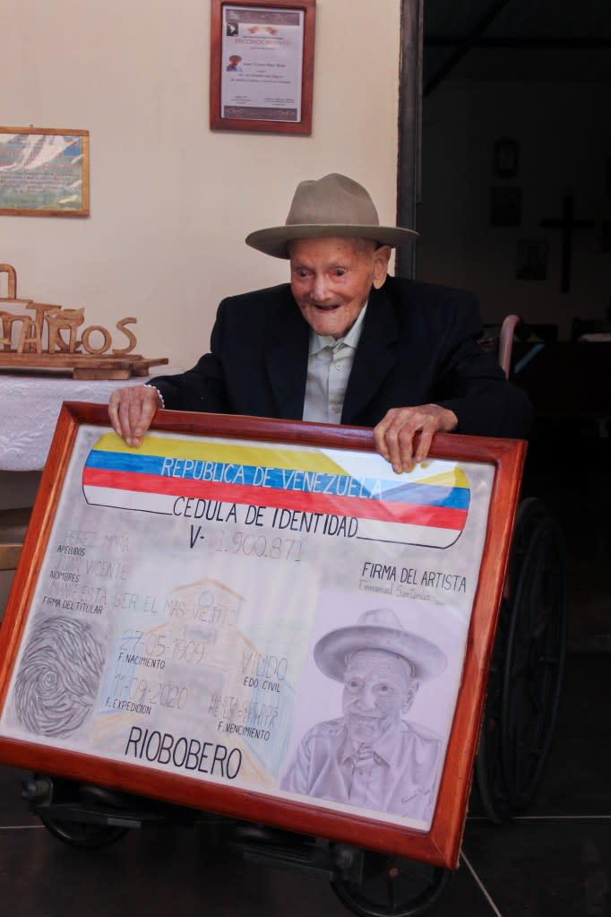 Juan Vicente Perez Mora poses for a photograph with a portrait of his identification card. NurPhoto via Getty Images