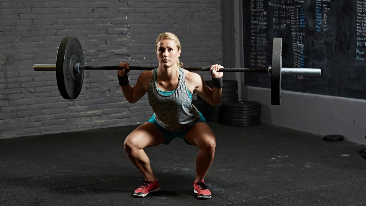  Woman performing the barbell back squat. 