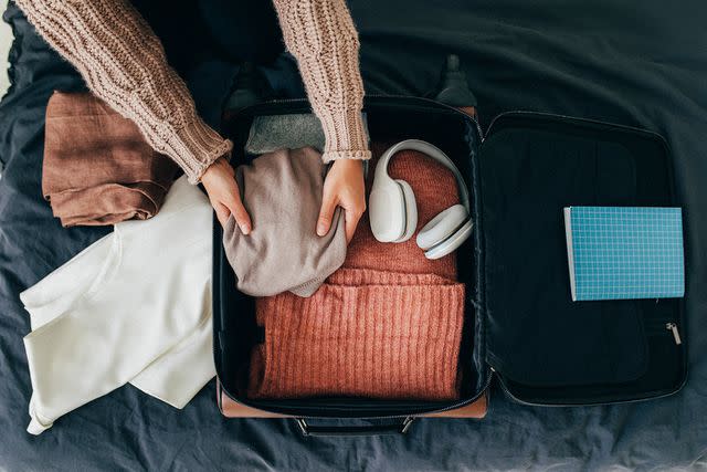 <p>Getty</p> Person packing comfy clothes in suitcase