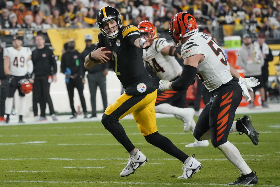 Pittsburgh Steelers quarterback Mason Rudolph (2) rushes for a first down as he looks to Cincinnati Bengals linebacker Logan Wilson (55) during the first half of an NFL football game Saturday, Dec. 23, 2023, in Pittsburgh. (AP Photo/Gene J. Puskar)