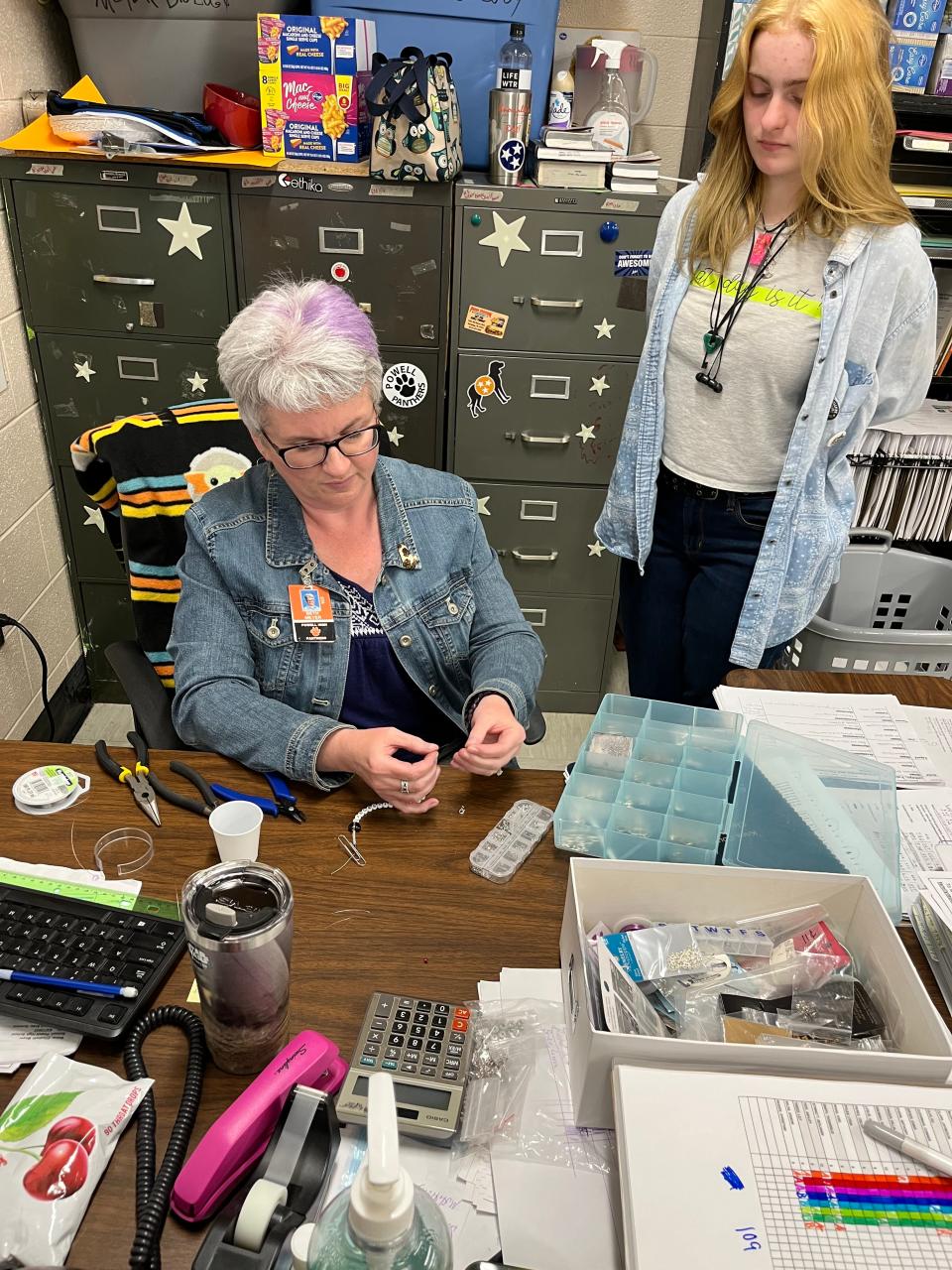 Beth Meyer helps a student finish a jewelry project during their 30-minute Panther Paws session of jewelry making at Powell High School.