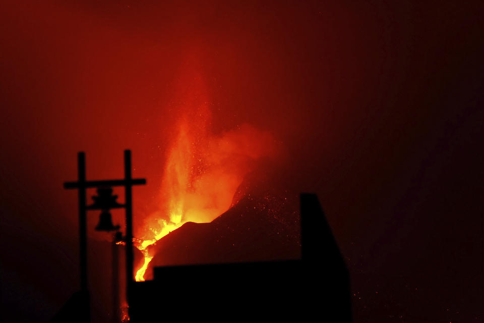 A volcano continues to spew out lava behind a church in Tajulla on the Canary island of La Palma, Spain in the early hours of Sunday, Oct. 10, 2021. A new river of lava has belched out from the La Palma volcano, spreading more destruction on the Atlantic Ocean island where molten rock streams have already engulfed over 1,000 buildings. The partial collapse of the volcanic cone has sent a new lava stream heading toward the western shore of the island. (AP Photo/Daniel Roca)