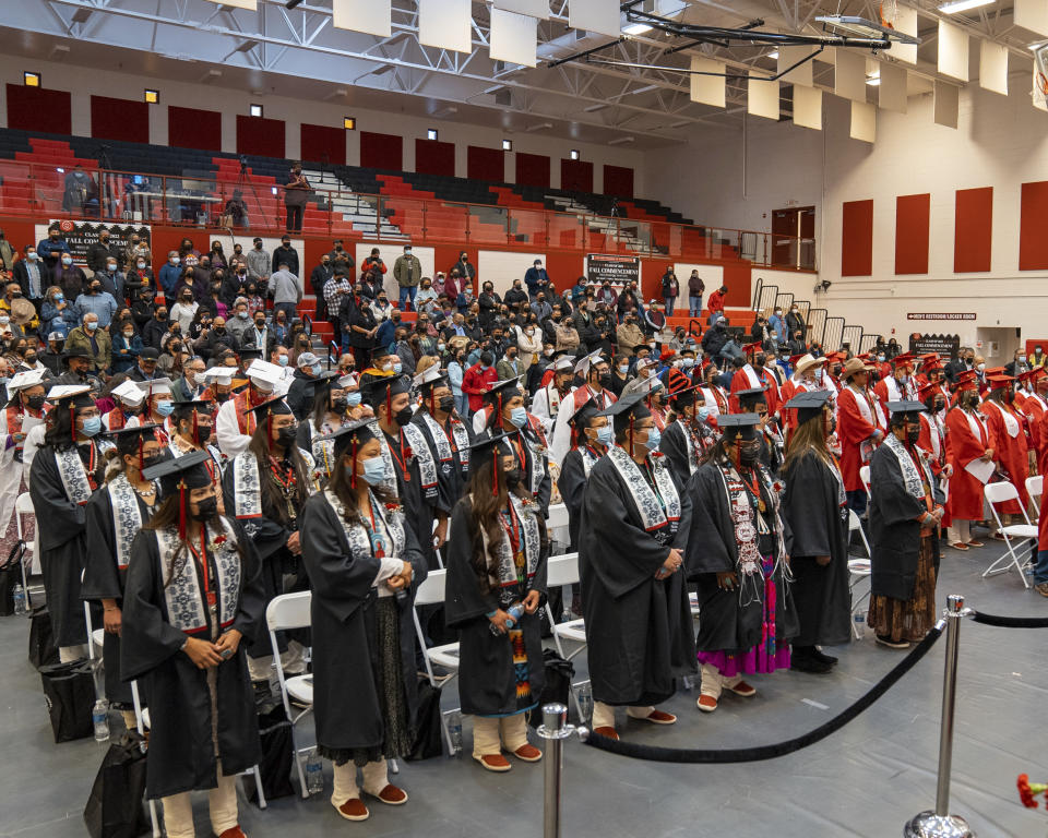 In this photo provided by Navajo Technical University, graduates at the school stand during a ceremony in Crownpoint, N.M., Dec. 16, 2022. On Friday, March 24, 2023, school officials said the creation of a doctoral program focused on Dine culture and language marks a milestone for the university and is the first doctoral program among tribal colleges and universities in the United States. (Wafa Hozien/Navajo Technical University via AP)