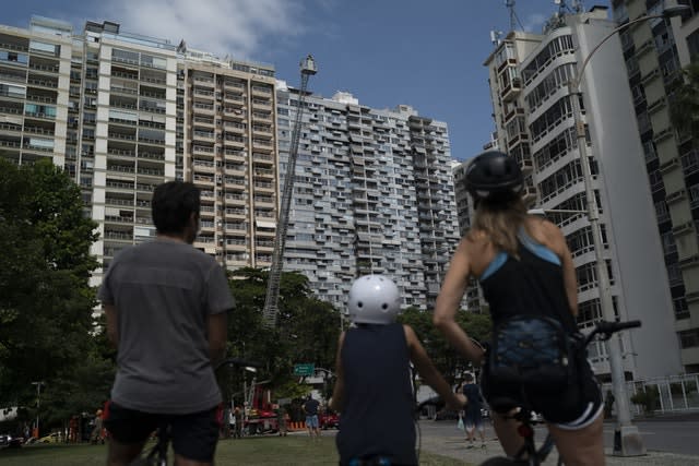 People watch firefighter Elielson Silva play his trumpet from the top of a ladder in Rio