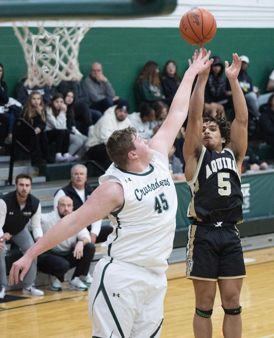 Aquinas' Bronson Gilyard shoots in the first half with pressure from Central's Jonathan Stangl at Central Friday, Dec. 29, 2023.