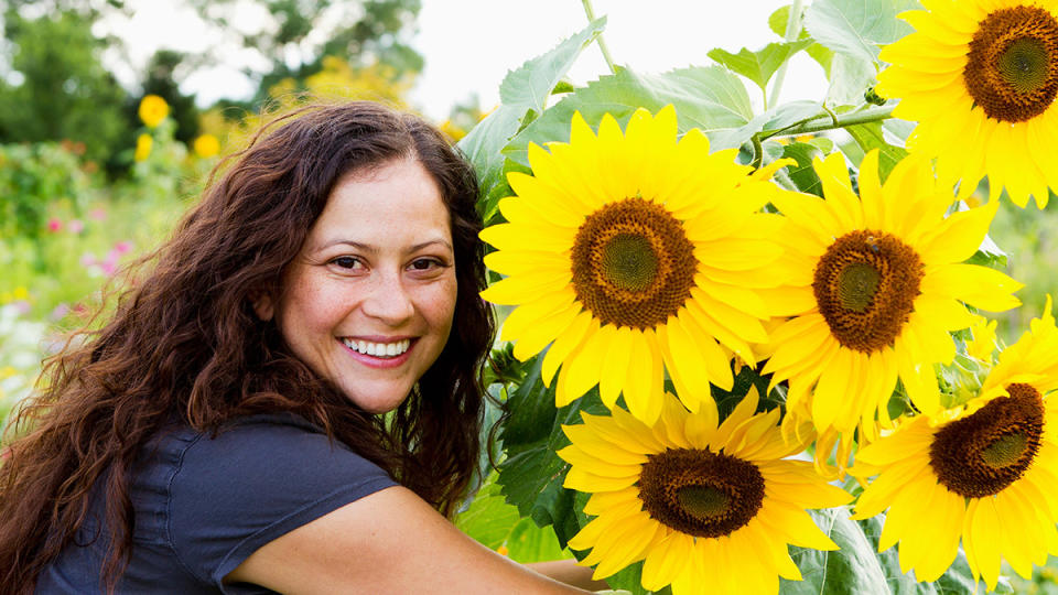 Woman with long, lush hair in a field of sunflowers from which they extract oil