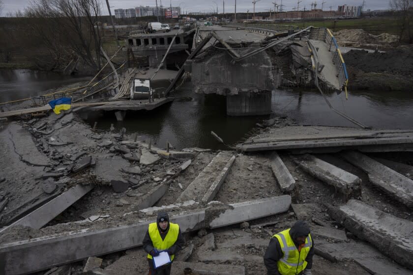 Ukrainian engineers on Wednesday inspect a damaged bridge that connects Kyiv with Irpin.