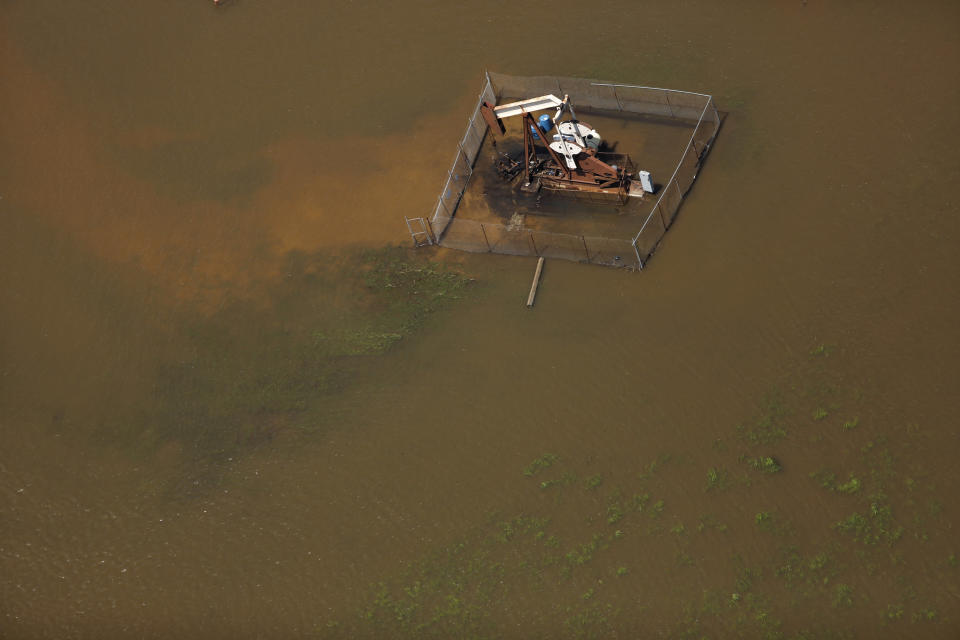 A pump jack oil well is seen immersed in floodwaters.