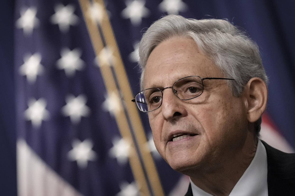 Attorney General Merrick Garland speaks, with an American flag in the background.