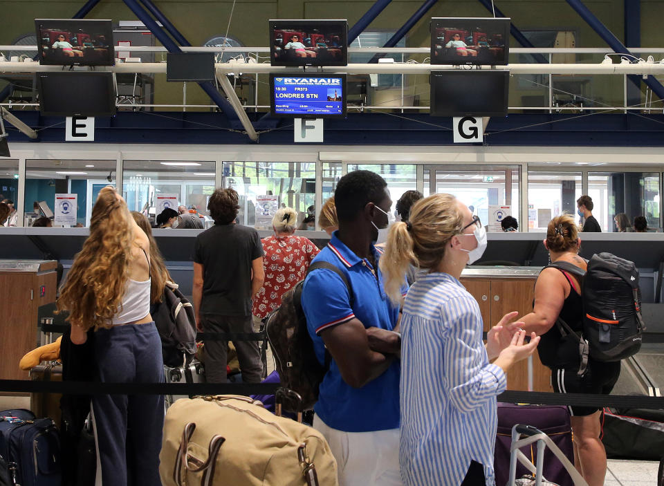 People check-in for a flight to London at the Biarritz airport, southwestern France, Friday Aug.14, 2020. British holidaymakers in France were mulling whether to return home early Friday to avoid having to self-isolate for 14 days following the U.K. government's decision to reimpose quarantine restrictions on France amid a recent pick-up in coronavirus infections. (AP Photo/Bob Edme)