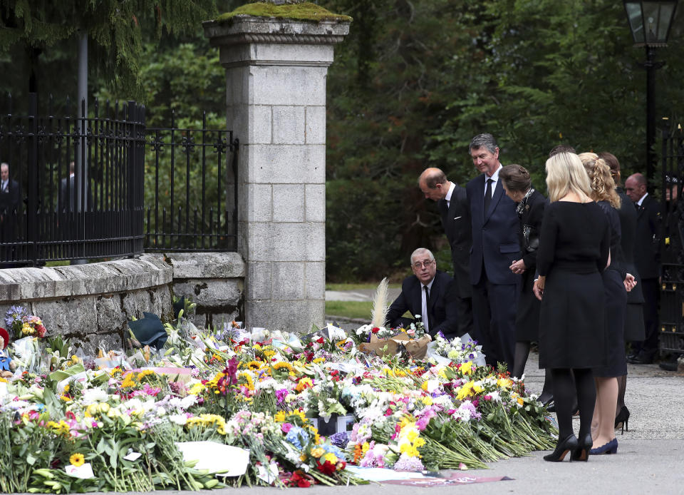 Members of the royal family look at floral tributes for Queen Elizabeth II, as others look on, outside the gates of Balmoral Castle in Aberdeenshire, Scotland Saturday, Sept. 10, 2022. Queen Elizabeth II, Britain's longest-reigning monarch and a rock of stability across much of a turbulent century, died Thursday after 70 years on the throne. She was 96. (AP Photo/Scott Heppell)