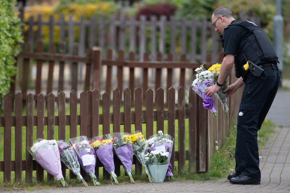 <p>A police officer carries flowers near the scene in Constable Road, Corby, Northamptonshire, following the fatal stabbing of a 16-year-old boy on Tuesday. Picture date: Wednesday May 26, 2021.</p>
