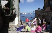 Children look on at the capsized Costa Concordia cruise liner (background) after the start of the "parbuckling" operation outside Giglio harbour September 16, 2013. REUTERS/Tony Gentile