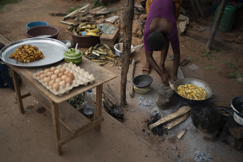 A woman prepares traditional food known as alloco, fried bananas, to sell on the street during a celebration for the return of the former Ivorian president Laurent Gbagbo in Mama, Ivory Coast, Saturday, June 19, 2021. The town's residents and people from other villages say that they will keep celebrating every day until Gbagbo arrives in his hometown. After nearly a decade, the ex-president returned to his country after his acquittal on war crimes charges that was upheld at the International Criminal Court earlier this year. (AP Photo/Leo Correa)