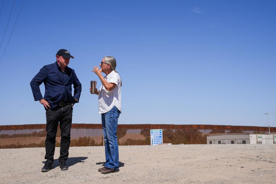 U.S. Sen. Mark Kelly speaks on Aug. 10, 2022, to Barbara Cook who lives across the road from the Morelos Dam in Yuma. Cook has lived next to the border wall for nine years and frequently sees migrants, who cross between gaps in the wall, pass by her home. On one occasion, migrants knocked on her door asking for water due to the hot weather.